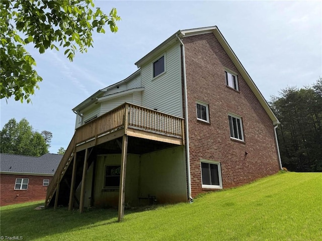 rear view of house with a wooden deck, a lawn, and brick siding