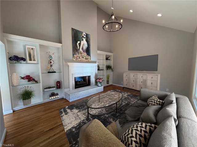 living room featuring wood finished floors, high vaulted ceiling, a chandelier, a fireplace, and baseboards