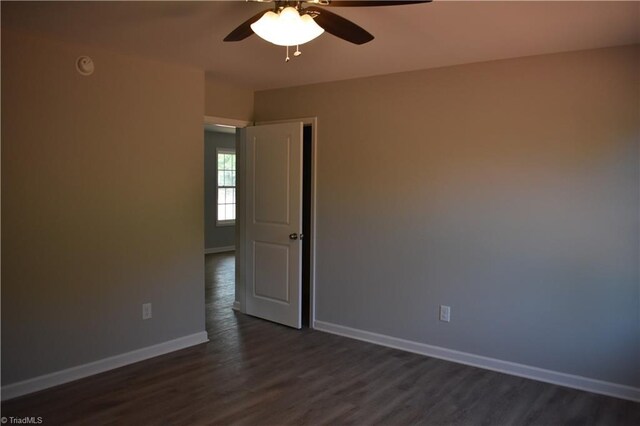 unfurnished room featuring dark wood-type flooring and ceiling fan