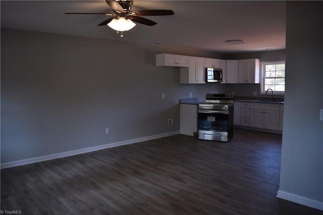 kitchen with appliances with stainless steel finishes, white cabinetry, sink, dark hardwood / wood-style floors, and ceiling fan