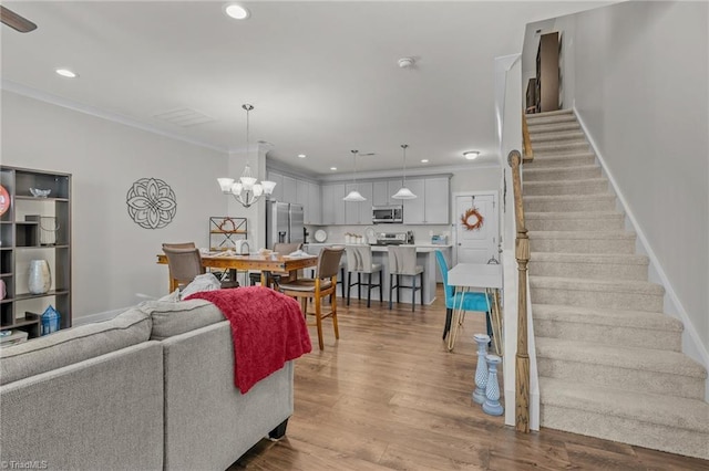 living room with crown molding, a notable chandelier, and light hardwood / wood-style floors