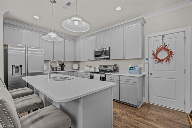 kitchen with pendant lighting, sink, a kitchen breakfast bar, stainless steel appliances, and an island with sink