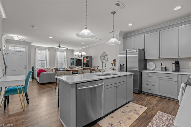 kitchen with pendant lighting, an island with sink, gray cabinetry, ornamental molding, and stainless steel appliances