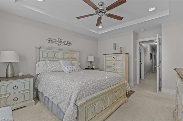 carpeted bedroom with ceiling fan and a tray ceiling