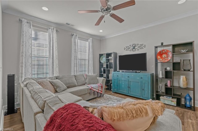 living room with crown molding, ceiling fan, and light wood-type flooring