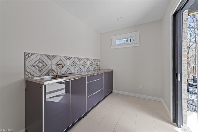 kitchen with baseboards, stainless steel countertops, modern cabinets, gray cabinets, and backsplash