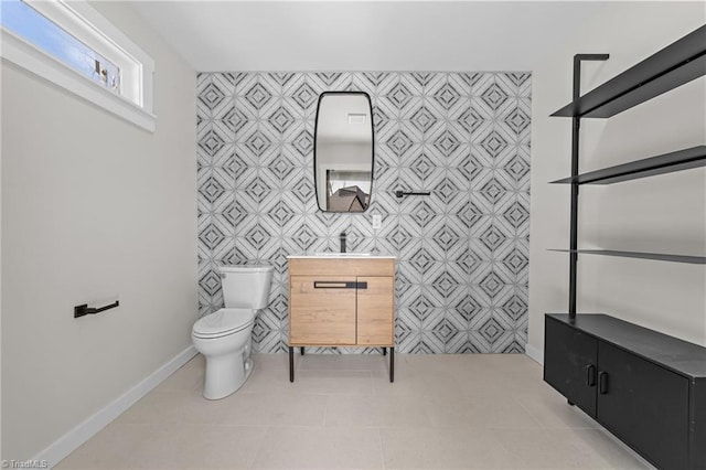 bathroom with baseboards, toilet, tile patterned floors, vanity, and tile walls