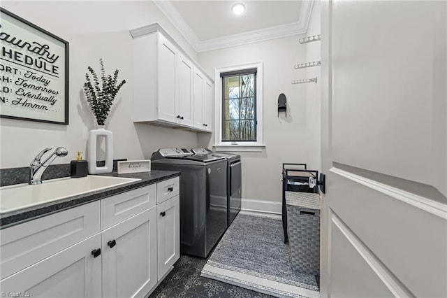 washroom with cabinet space, baseboards, ornamental molding, washing machine and dryer, and a sink