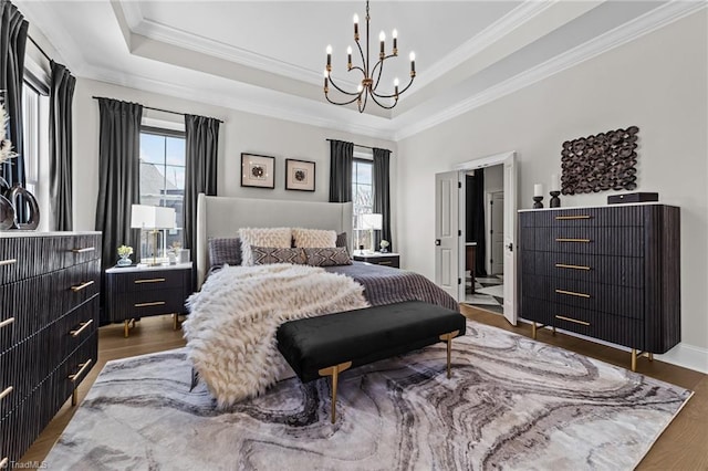 bedroom featuring crown molding, a chandelier, a raised ceiling, and wood finished floors