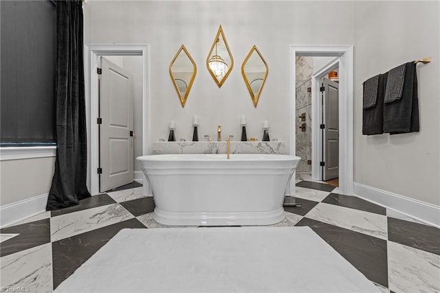 full bathroom featuring marble finish floor, a soaking tub, and baseboards