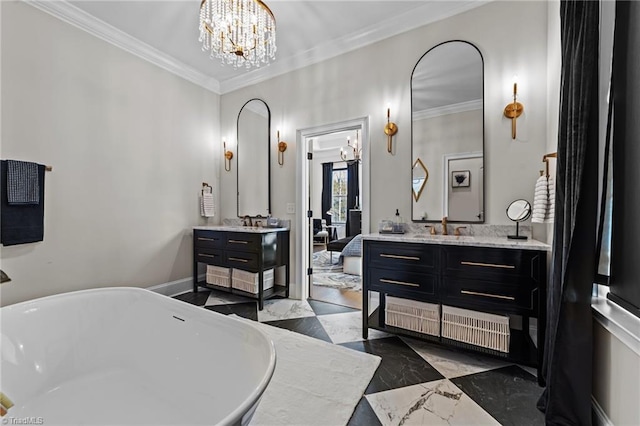 bathroom featuring crown molding, a notable chandelier, two vanities, a freestanding bath, and a sink