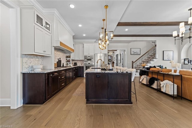 kitchen featuring tasteful backsplash, an inviting chandelier, white cabinetry, dark brown cabinetry, and wood finished floors