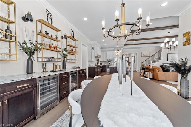 dining room with a chandelier, beverage cooler, crown molding, and stairs