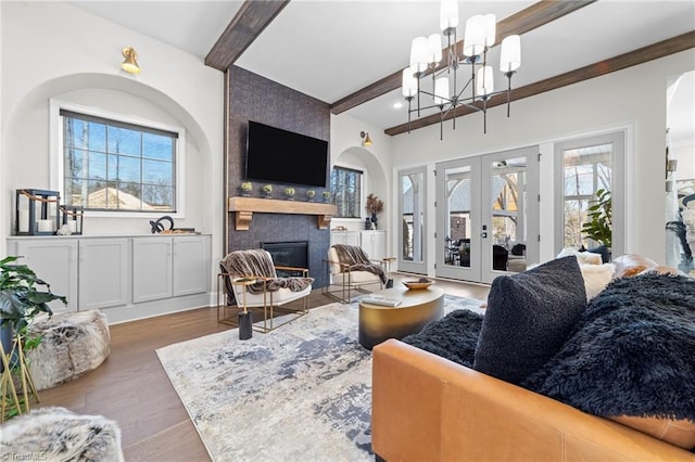 living area featuring a large fireplace, beamed ceiling, plenty of natural light, and wood finished floors