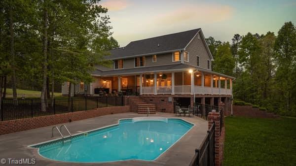 back house at dusk with a patio and a fenced in pool