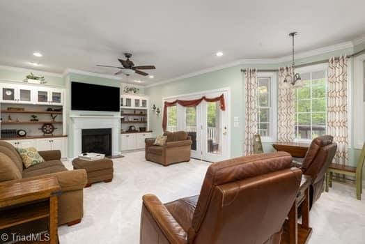 living room featuring ceiling fan with notable chandelier and crown molding