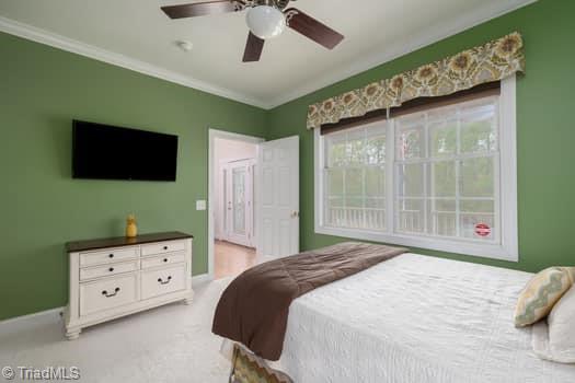 bedroom featuring ceiling fan, crown molding, and light colored carpet