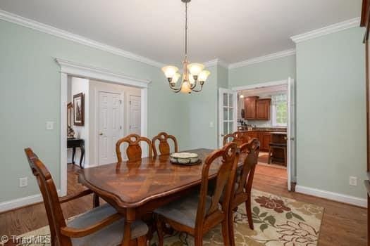 dining space featuring ornamental molding, light hardwood / wood-style floors, and a chandelier