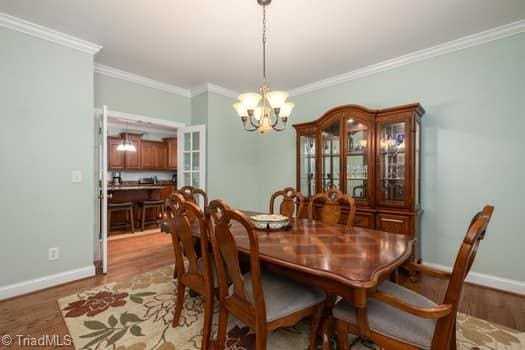 dining area with an inviting chandelier, ornamental molding, and light hardwood / wood-style floors