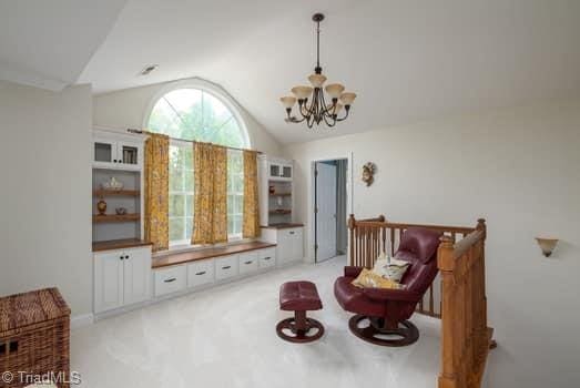 living area with an inviting chandelier, lofted ceiling, and light carpet