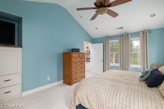 carpeted bedroom with ceiling fan and vaulted ceiling