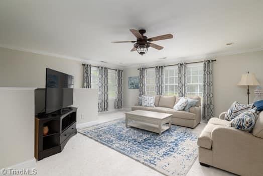 living room with ceiling fan and ornamental molding