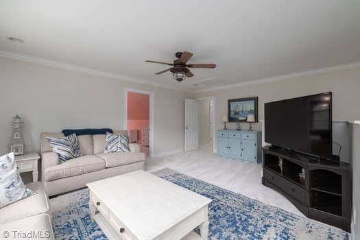 carpeted living room with ceiling fan and crown molding