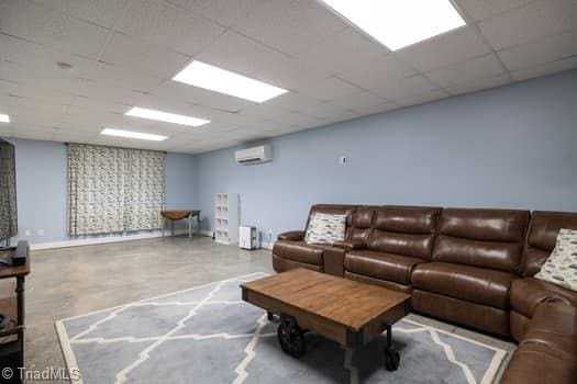 living room featuring a drop ceiling and a wall mounted air conditioner