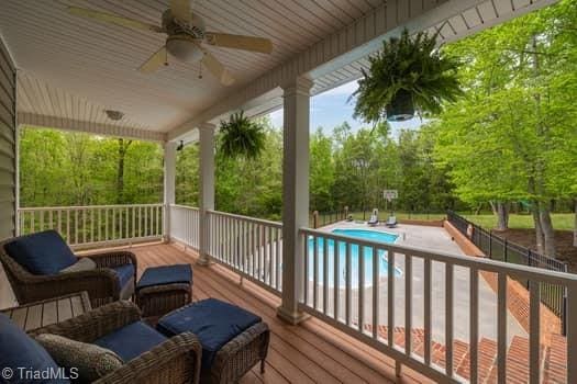 deck featuring ceiling fan and a fenced in pool