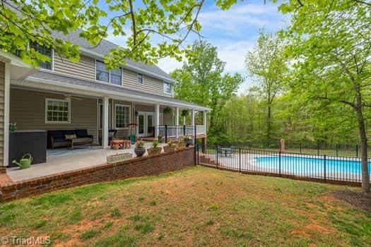 rear view of house with a lawn, french doors, a fenced in pool, and a patio