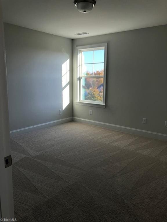 unfurnished room featuring dark carpet, baseboards, and visible vents