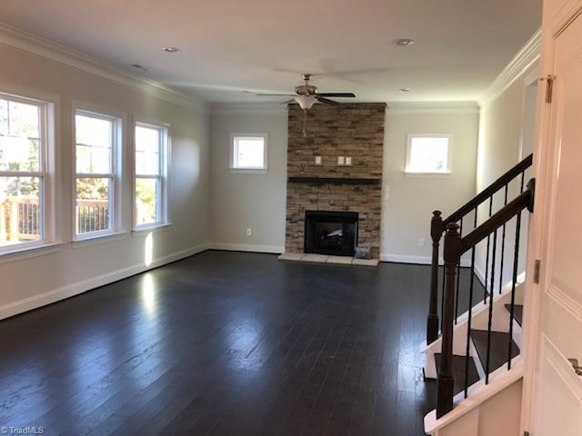 unfurnished living room featuring baseboards, ornamental molding, a stone fireplace, a ceiling fan, and dark wood-type flooring