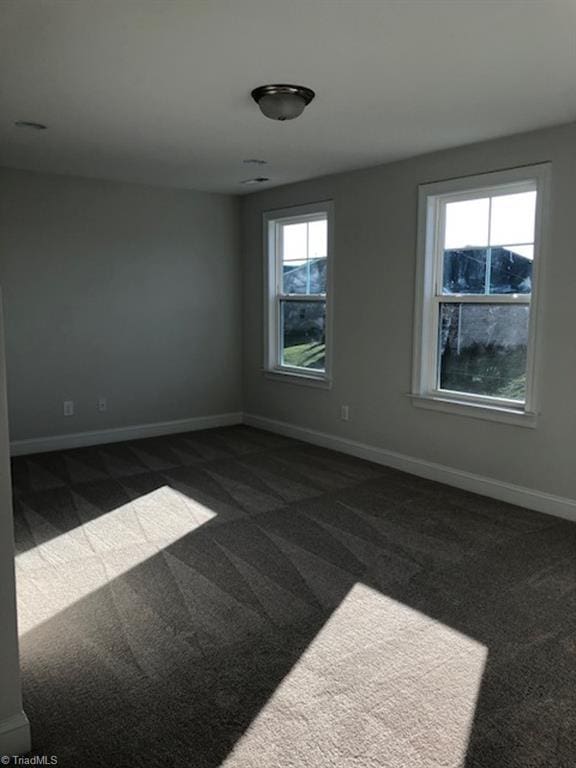 empty room with dark colored carpet and baseboards