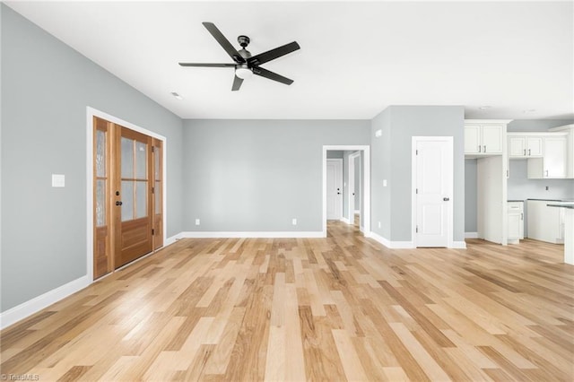 unfurnished living room featuring light wood finished floors, baseboards, and ceiling fan