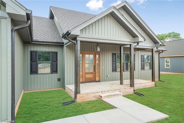back of property featuring roof with shingles, a yard, board and batten siding, and a porch