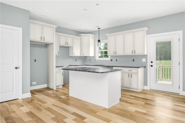 kitchen featuring light wood-style floors, a kitchen island, dark countertops, decorative light fixtures, and recessed lighting