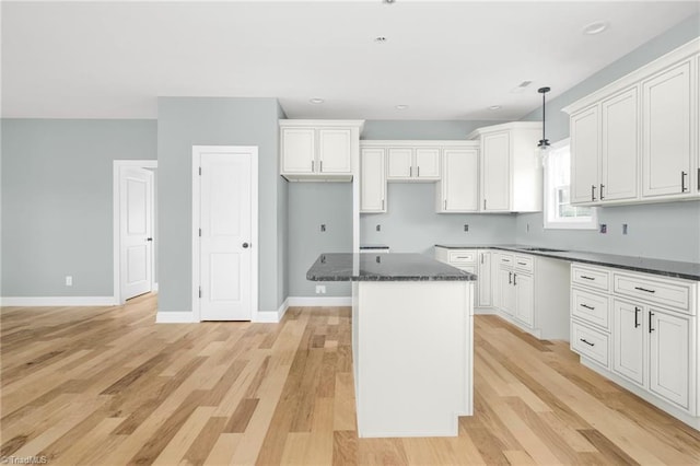 kitchen featuring a kitchen island, light wood finished floors, white cabinetry, baseboards, and decorative light fixtures