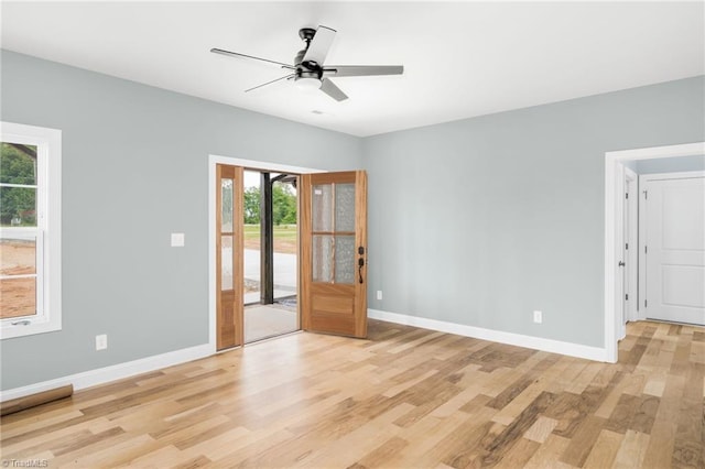 unfurnished room featuring healthy amount of natural light, light wood finished floors, baseboards, and ceiling fan
