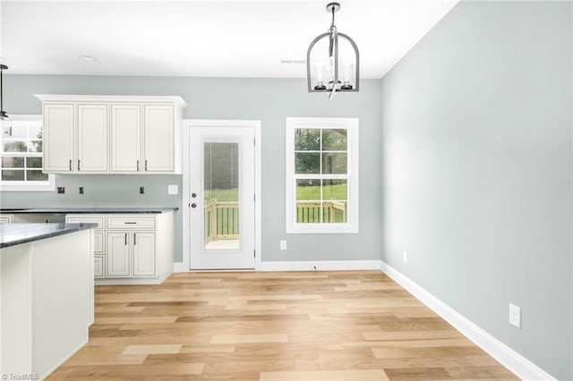 unfurnished dining area with light wood finished floors, a chandelier, and baseboards