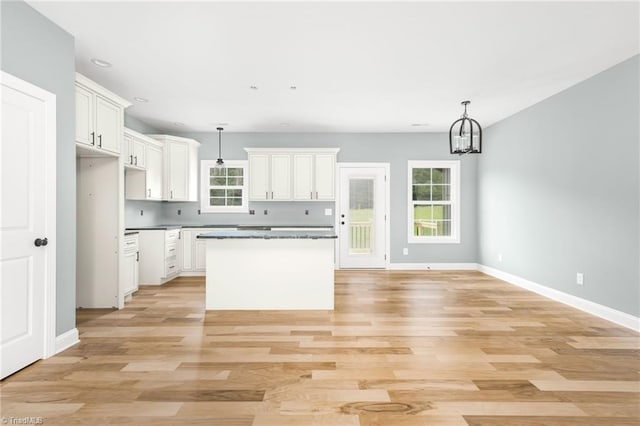 kitchen featuring a kitchen island, a chandelier, white cabinetry, pendant lighting, and baseboards