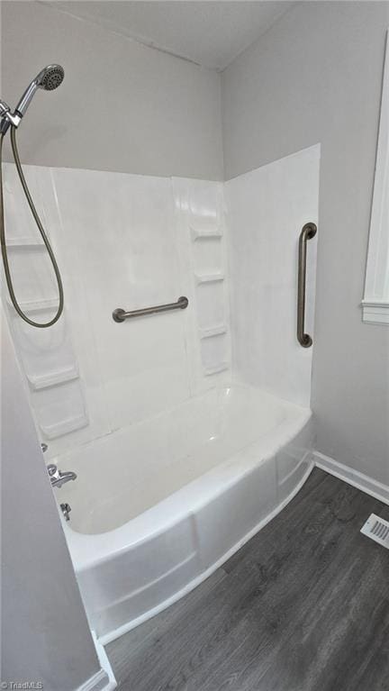 bathroom with visible vents, baseboards, shower / bathing tub combination, and wood finished floors