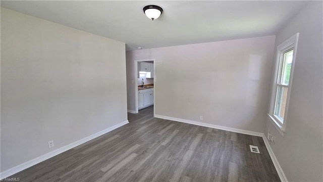 spare room with dark wood-type flooring, baseboards, and a sink