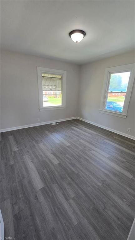 spare room featuring a wealth of natural light, dark wood-style floors, and baseboards