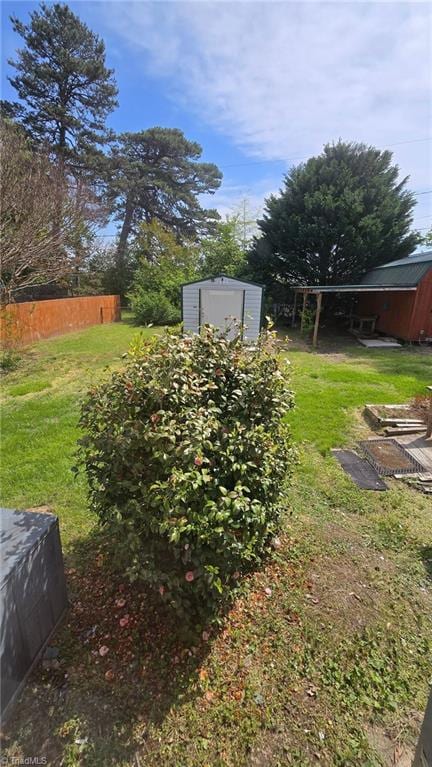 view of yard featuring fence, an outdoor structure, and a shed