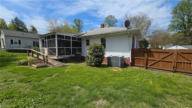 back of property featuring a sunroom, central AC unit, a gate, and a lawn