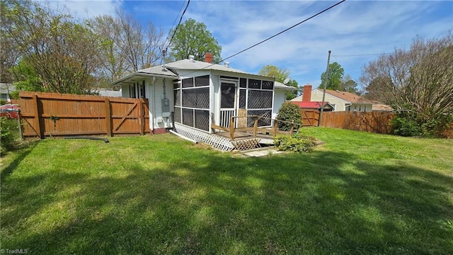 rear view of house with a yard, a sunroom, a fenced backyard, and a chimney