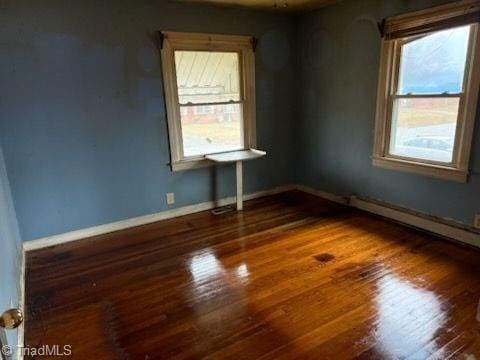 spare room with baseboards and wood finished floors