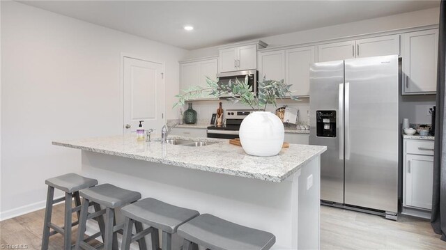 162 W Farm Loop, Stokesdale, NC 27537 - kitchen featuring a sink, a kitchen breakfast bar, light wood-style floors, light stone countertops, and stainless steel appliances