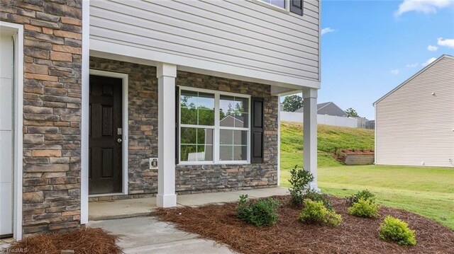162 W Farm Loop, Stokesdale, NC 27537 - entrance to property featuring stone siding, a lawn, and covered porch