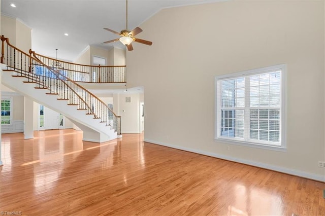 unfurnished living room featuring light hardwood / wood-style flooring, high vaulted ceiling, plenty of natural light, and ceiling fan